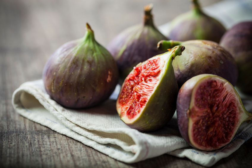 Whole and sliced figs on a folded linen on wood table